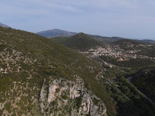 Aerial drone view dragon hole of St. George in the mountain ridge next to the river louros and the roman aqueduct of ancient nikopolis in preveza, epirus, greece.