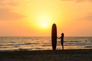 Fototapeta na wymiar Surfista al tramonto guarda il mare della Versilia. 