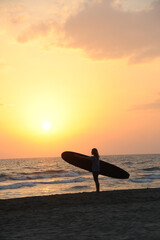 Surfista al tramonto guarda il mare della Versilia.
