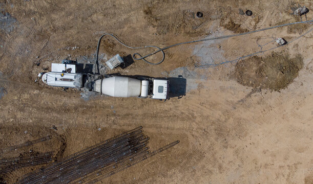 Aerial. Concrete mixer truck delivers concrete through a long hose. Top view from drone.