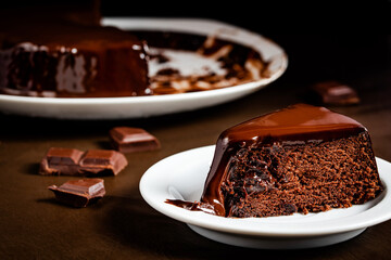 Chocolate cake slice in the white plate on the table.