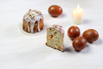 Easter cake, colored eggs, burning candle on white background
