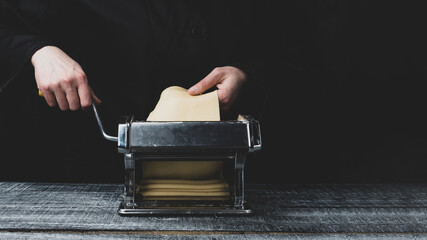 roll out the dough on a pasta machine on a dark wood