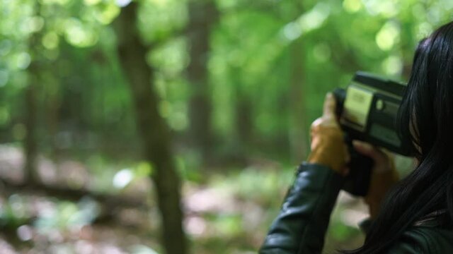 Beautiful hobbyist woman recording on old film video camera in the woods - close up revolving gimbal shot in circular motion