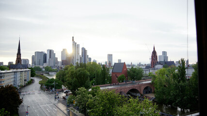 Naklejka premium Skyline von Frankfurt über den Abend vom Sonnenuntergang bis zur Dämmerung und Abendröte mit den Hochhäusern im Hintergrund und der Alten Brücke mit neuem Portikus im Vordergrund