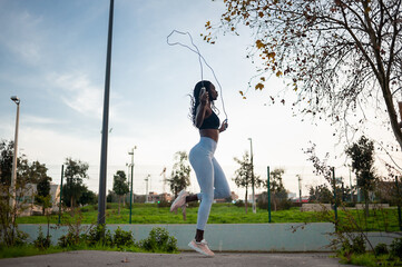 profile view of a black woman jumping rope on the street. Outdoor exercise, fitness routine