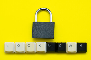 closed padlock with keys on a yellow background at the bottom the inscription lockdown laid out from the keys of a computer keyboard concept prohibitions data protection