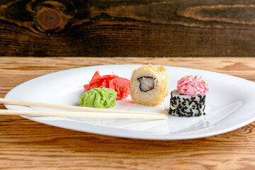 sushi rolls wasabi ginger and chopsticks on a plate on the table