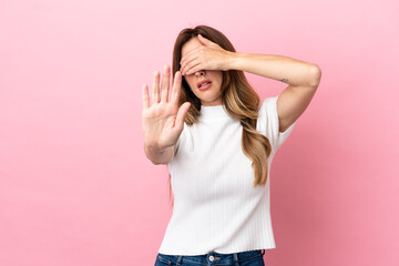 Obraz na płótnie Canvas Caucasian woman isolated on pink background making stop gesture and covering face