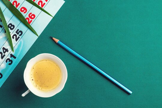 Palm Leaf, Calendar, Coffee Cup And Pencil On Green Table Surface. Business And Planning