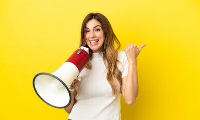 Caucasian woman isolated on yellow background shouting through a megaphone and pointing side