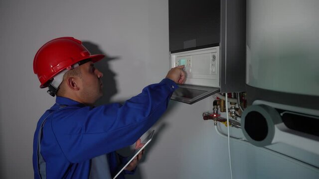 Modern technician man setting heating system settings with tablet computer