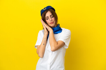 Airplane stewardess woman isolated on yellow background making sleep gesture in dorable expression