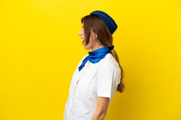 Airplane stewardess woman isolated on yellow background laughing in lateral position