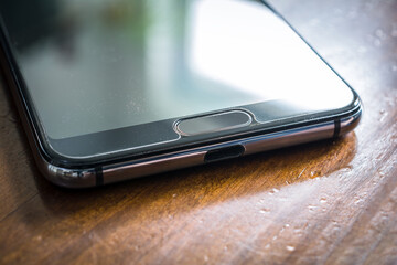 Black Smartphone With Window Reflection Lying On A Brown Wooden Table
