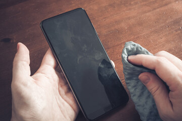 Cleaning A Smartphone Screen Of Dust, Dirt And Fingerprints With A Cleaning Wipe Over A Table