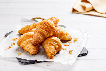 Board with tasty croissants on dark wooden table, closeup.