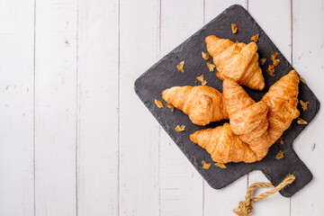 freshly baked croissants on white wooden table, top view