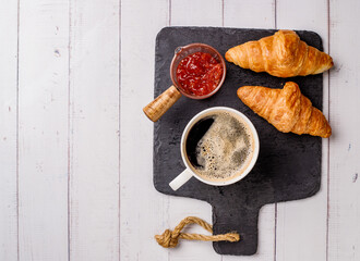 Coffee white cup, croissants on white wooden table background, selective focus. Breakfast concept