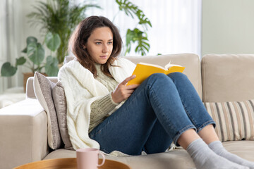 Young woman reading book at home.