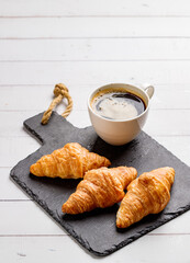 Coffee white cup, croissants on white wooden table background, selective focus. Breakfast concept