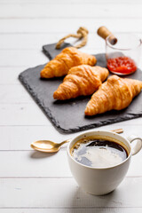 Coffee white cup, croissants on white wooden table background, selective focus. Breakfast concept