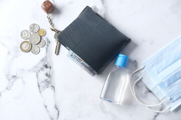 wallet, coins, hand sanitizer and mask on table 