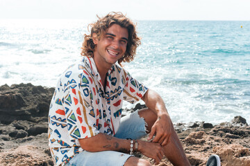Young caucasian man relaxing on the beach and walking for the rocks