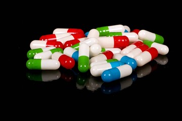 heap of colorful capsules are lying on a black ground