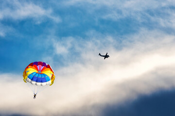 Fototapeta na wymiar Paragliding using a parachute on background of blue cloudy sky.