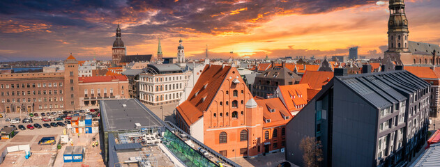 Beautiful aerial view of the Riga old town with St. Peters cathedral in the center and epic sunset sky.