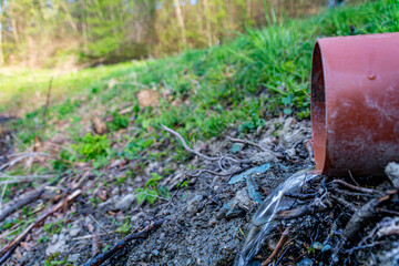 Pure water flowing in a drain from the plastic pipe on forestal background