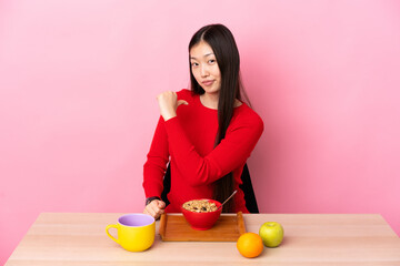 Young Chinese girl  having breakfast in a table proud and self-satisfied