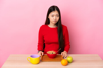Young Chinese girl  having breakfast in a table with sad expression