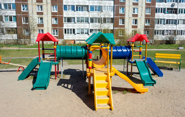 Fototapeta na wymiar Colorful plastic children's town with slides and ladders on the Playground in the courtyard of high-rise buildings