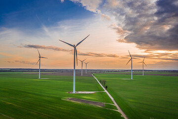 Wind turbines at dusk on green field. Renewable energy, Poland.