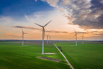 Fototapeta na wymiar Wind turbines at dusk on green field. Renewable energy, Poland.