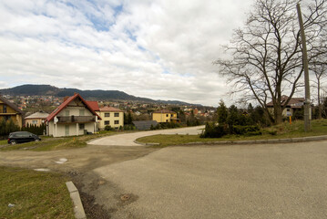 Fototapeta na wymiar Wide angle panorama shot of an A shaped houses against mountains and hills in a countryside of South Polish town during day time. Limanowa, Lesser Poland. Europe