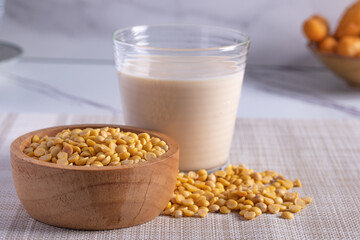 Soy milk in transparent glass and soybean seeds on gray background