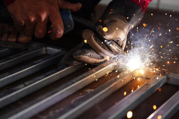 The hand of a male worker welding a sparks a close-up
