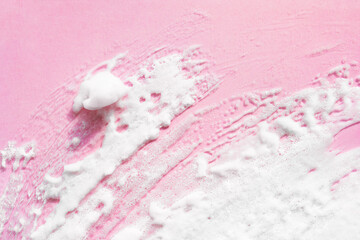 White smear of foam on pink background. Macro bubble creme, shaving foam, mask texture swatch of cosmetics facial