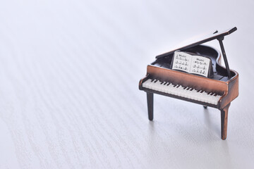 白い木目を背景にしたグランドピアノの明るいイメージ
