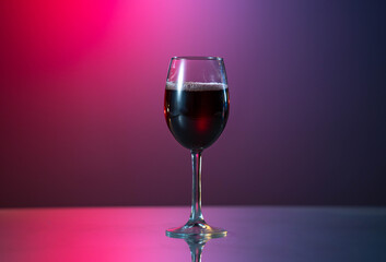 red wine is poured from a bottle into a glass. on the table with reflected surface