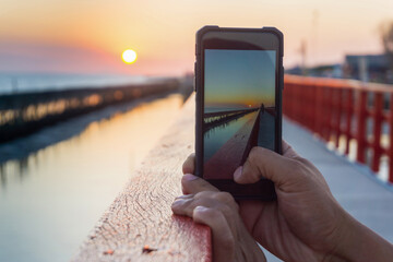 Man taking picture of the sunset with mobile phone.