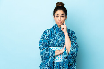 Woman wearing kimono over isolated background and thinking