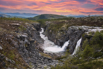beautiful waterfalls with crystal clear water with mountains in the background at sunset Norway.