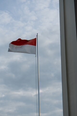 The Indonesian flag in red and white is flying in front of a building.