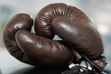 Brown leather boxing gloves lie on a black punching bag. Sport equipment. Training. The fight. Sparring                             