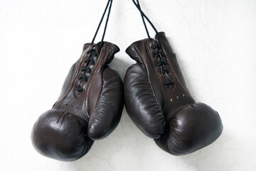 Brown leather boxing gloves lie on a black punching bag. Sport equipment. Training. The fight. Sparring                             
