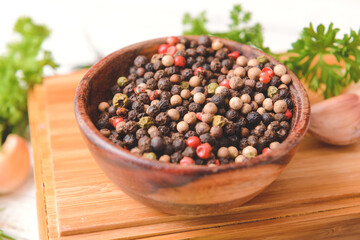 Bowl with peppercorns on light wooden background